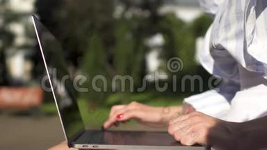 在<strong>公园里坐在</strong>长椅上的一个工作在笔记本电脑上的女商人